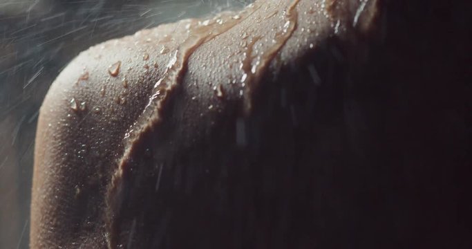 Cinematic shot of a beautiful woman in the shower who washes herself in slow motion. 