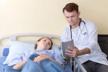 Obraz premium Medical professionals caucasian man recording and taking information to tablet at patients bed.Copy space.