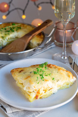 Piece of cheesy scalloped potatoes or potato gratin on a plate, holiday theme, vertical