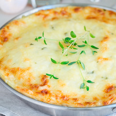 Cheesy scalloped potatoes or potato gratin in a baking dish, holiday theme, square format