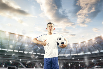 Young boy with soccer ball doing flying kick at stadium. football soccer players in motion on sky...