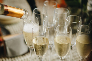 Sommelier pours champagne from a bottle into a glass at the table in the restaurant.