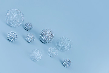 Silver shiny Christmas bauble decoration on pastel blue background.