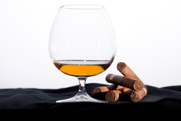 Glass of cognac with cigars on white
