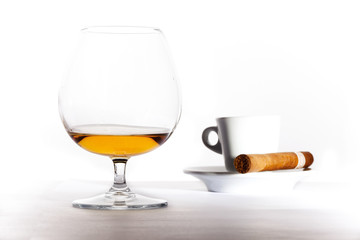 Glass of cognac with coffee and cigar on white background