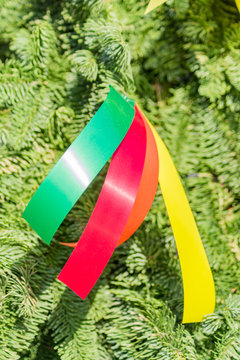 close up of christmas tee decorated with multicolored satin ribbons of redm ellow and green colors, new year background