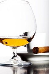 Glass of cognac with coffee and cigar on white background