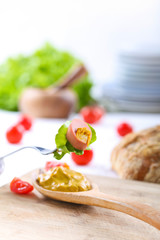 Slice of sausage with mustard and lettuce on fork