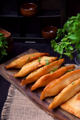 Fried chebureks with meat on a wooden board