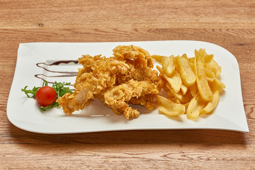 fried chicken thighs coated with corn flakes, french fries and tomato