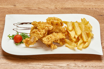fried chicken thighs coated with corn flakes, french fries and tomato