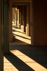 Fototapeta premium To mocne światło słoneczne tego poranka w Santa Fe w Nowym Meksyku uwydatnia mocne tekstury i cienie budynków z cegły glinianych wzdłuż ulicy na historycznym placu w centrum miasta.