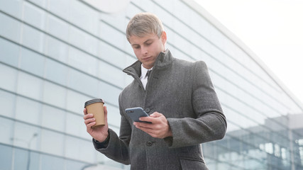 Portrait of handsome business man using smartphone and drinking 