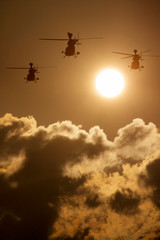 This photo illustration depicts three military helicopters flying towards a rising sun. The clouds also appear like smoke rising from below.