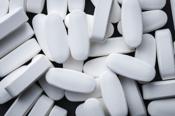 Scattered White Calcium Tablets Scattered On A Gray Slate Background. Vitamins, Pills. Top View. Medical Series.