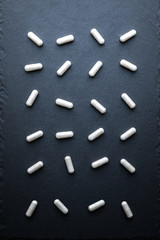 White Transparent Drugs, Pills, Vitamins (Glycine) Scattered On A Gray Slate Background. Medical Series. Top View.