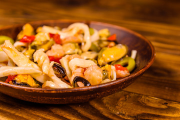 Ceramic plate with different sea food and olives on wooden table