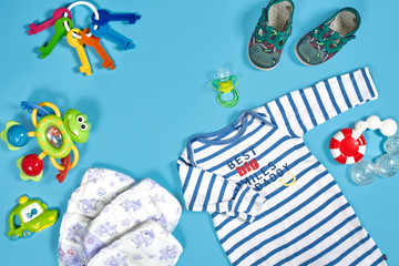 Baby clothing, toiletries, toys and health care accessories on blue background.