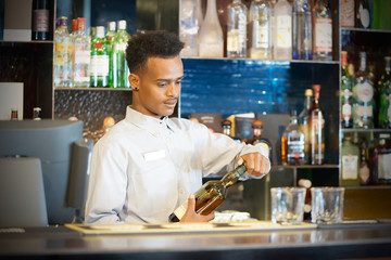 Bartender man pours whiskey to the client of the hotel bar. The concept of service. Focus on the bartender.
