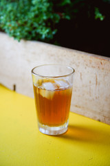 Summer coffee cocktail with tonic and ice cubes on a yellow table