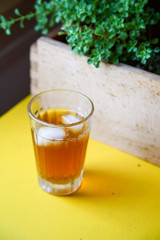 Summer coffee cocktail with tonic and ice cubes on a yellow table