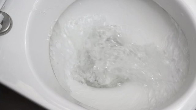 White toilet paper is flushed down the toilet.
