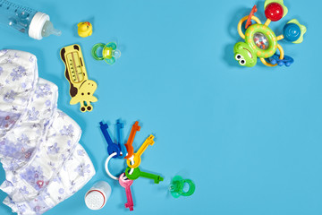 Babies goods: cloth diaper, baby powder, nibbler, cream, teether, soother, baby toy on blue...