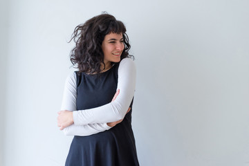 Fototapeta premium Portrait of a beautiful happy young woman in an elegant dress while standing in front of a white wall.