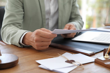 Male notary with documents at table in office, closeup