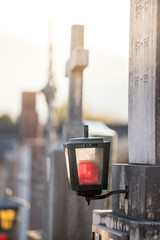 Lantern and stone cross on cemetery, sundown, leave