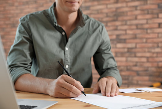 Male notary signing document at table in office, closeup