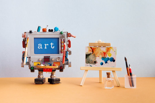 Art and artificial intelligence concept. Robotic computer with pencil brush and message Art on blue screen, handwritten watercolor abstract picture wooden easel. Gray brown background
