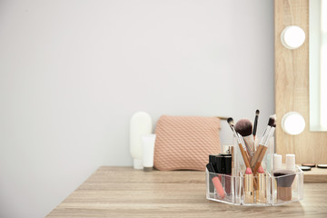 Makeup cosmetic products with tools in organizer on dressing table. Space for text