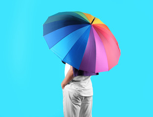 Man with rainbow umbrella on color background © New Africa