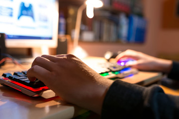 Young teenage boy playing video games on personal computer, focus on the boys hand.