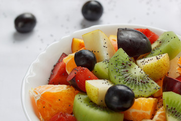 Fresh salad from kiwi, oranges, plums, grapes and chia seeds close up. Healthy lifestyle.