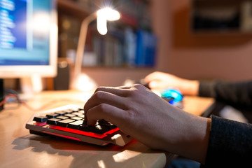Fototapeta premium Young teenage boy playing video games on personal computer, focus on the boys hand.