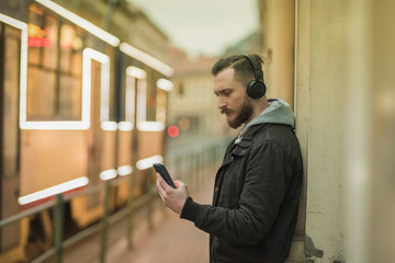 A retro style photo of a hipster man while checking his smartphone in an urban environment.