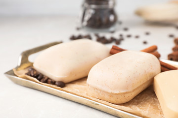 Different soap bars in tray with parchment paper on light table, closeup