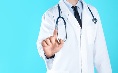 Male doctor pointing on color background, closeup