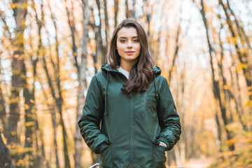 Beautiful young woman in jacket looking at camera in autumnal forest
