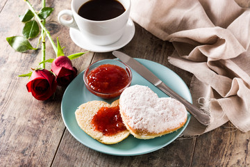 Valentine's Day breakfast with coffee, heart-shaped bun and berry jam.

