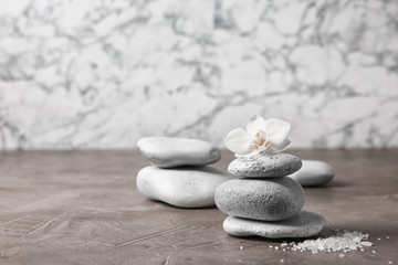 Spa stones and orchid flower on grey table. Space for text