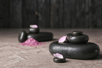 Spa stones and flower petals on table. Space for text