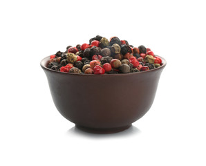 Bowl with different pepper grains on white background
