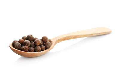 Wooden spoon with allspice pepper grains on white background