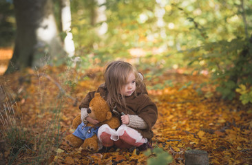 Fairy Girl Playing wiht Teddy Bear in Woods.Beautiful little girl in autumn forest
