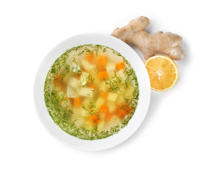 Bowl of fresh homemade soup to cure flu, lemon and ginger on white background, top view