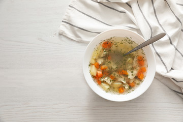Flat lay composition with bowl of fresh homemade soup to cure flu and space for text on wooden...