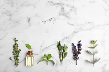 Essential oil in glass bottle, herbs and space for text on marble background, flat lay